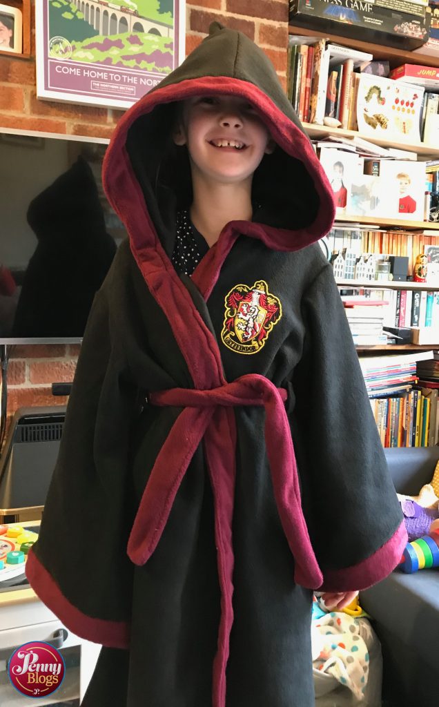 A ten yearly girl smiling whilst wearing a Harry Potter Dressing Gown with the hood up