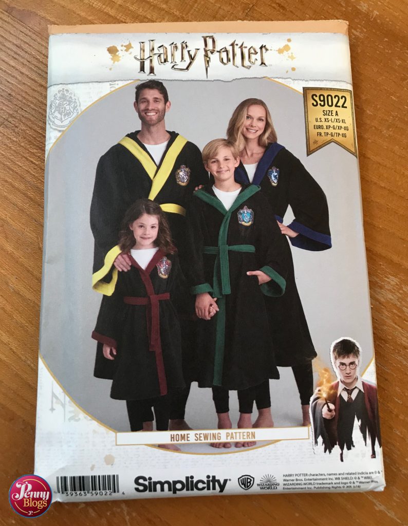 The packet of the Harry Potter dressing gown sewing pattern - simplicity pattern S9002 showing a family of four wearing dressing gowns, each one showing a different Hogwarts House colour on the trim